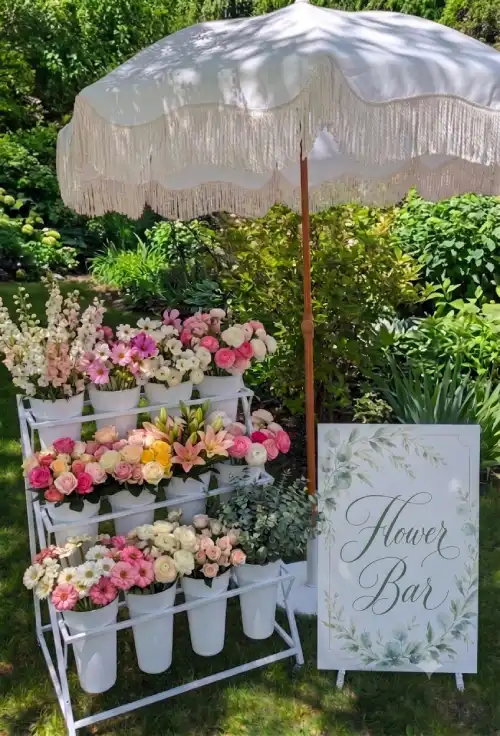 Outdoor flower bar rental in an Ottawa garden with roses, ranunculus and a Flower Bar sign on an easel